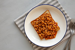 Homemade English Beans on Toast, top view. Overhead, from above,, a Food & Drink Photo by LiudmylaChuhunova