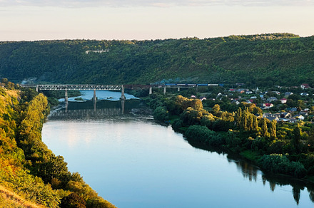 Peaceful river landscape with a bridge and tranquil village view, a Photo by AS photostudio