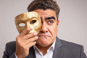 Man holding theatrical mask in contemplation, a Person Photo by AlyaAnd