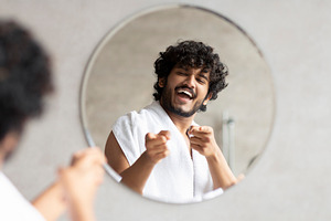 Excited indian guy pointing at mirror in bathroom with two fingers, standing wi, a Person Photo by Prostock-Studio