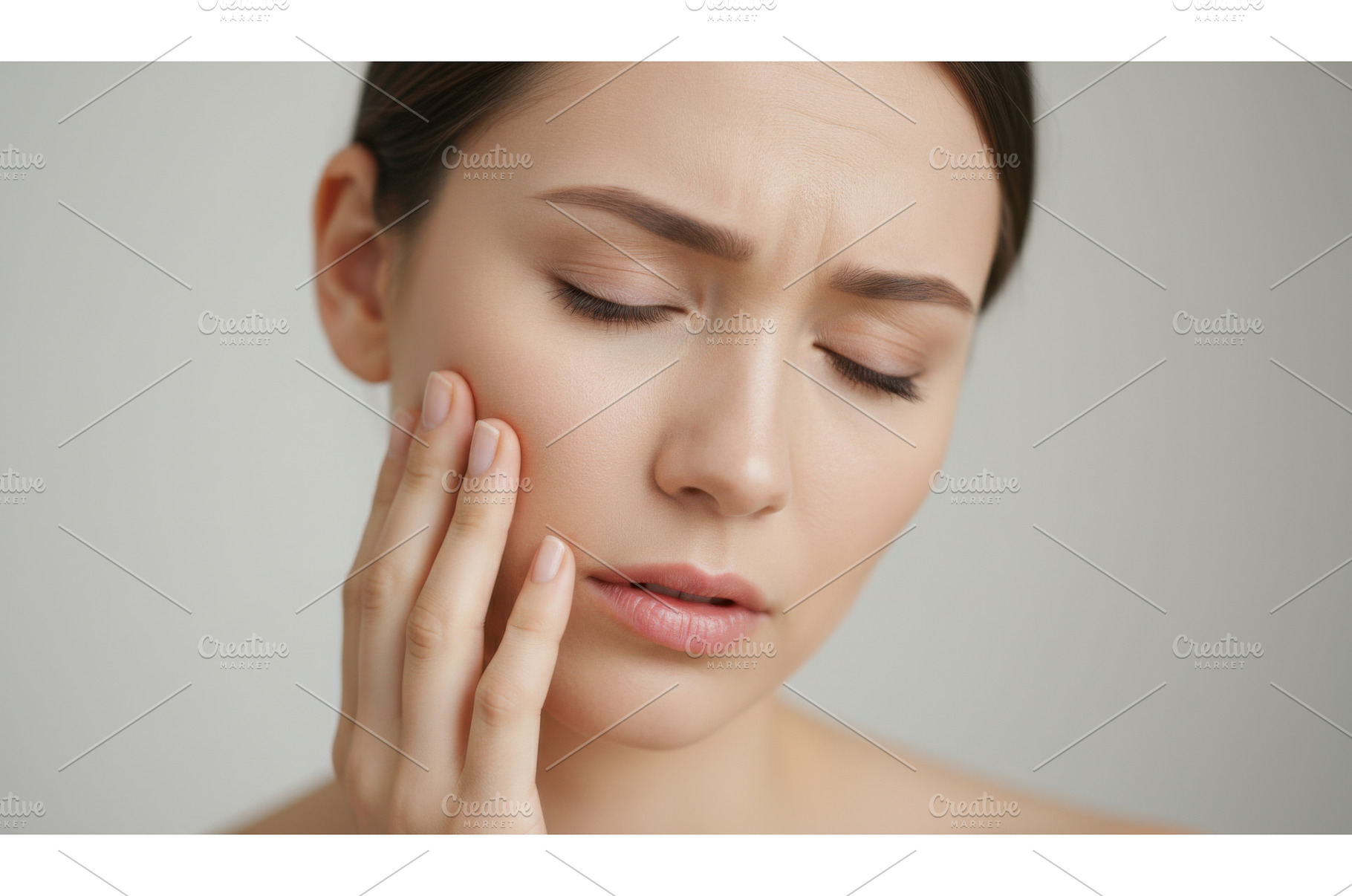 Young woman touching her cheek with, a Health & Medical Photo by Igor Tichonow