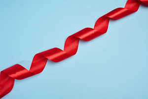 A red satin ribbon twisted into a spiral is placed diagonally on, a Background Photo by ndanko