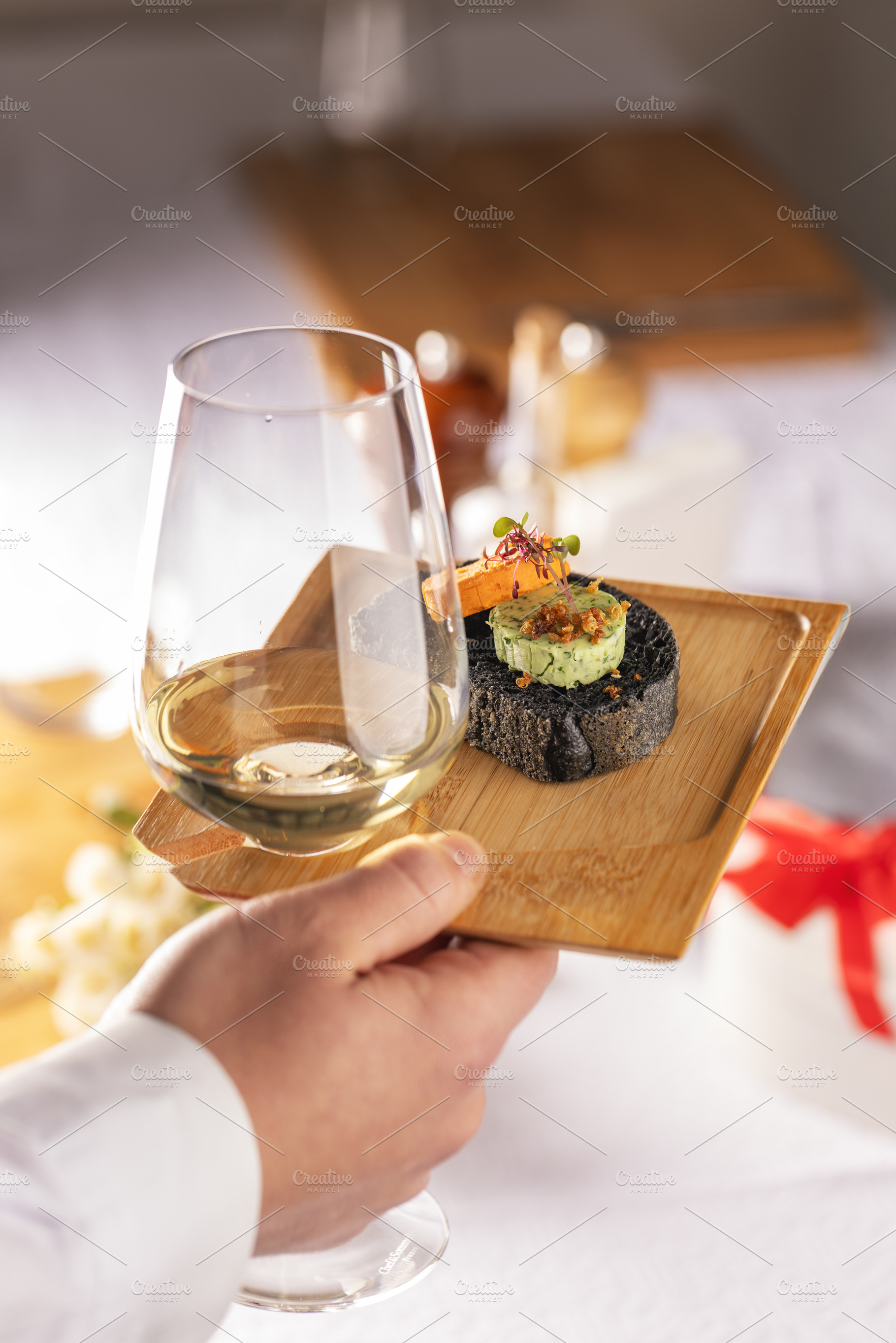 Waiter serving a glass of white wine and black bread canapes, a Photo by Grafvision photography