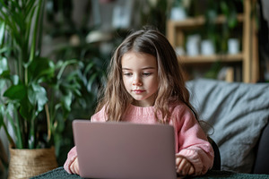 Cute little girl focused on laptop, a Photo by Pavel_design