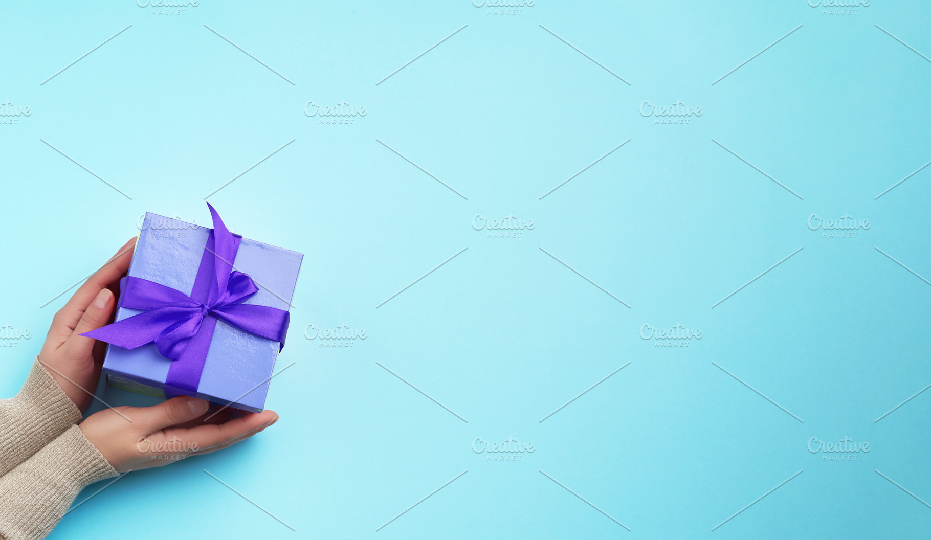 Female hands holding a blue gift box on a blue background, a Holiday Photo by ndanko