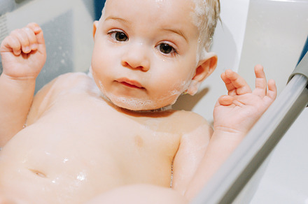 Portrait of a nine month old baby taking a bath in a baby bathtub