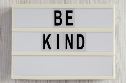 'Be kind' on a lightbox on a white wooden surface, top view. Fla, a Business Photo by LiudmylaChuhunova