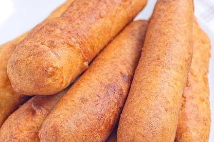 Stack of corn dogs on white plate, served with ketchup, vertical closeup, a Food & Drink Photo by iuliia_n
