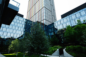 Modern glass building with landscaped green area and orange seating features, a Photo by AS photostudio