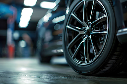 Car wheel with new tire on blurred garage background, a Transportation Photo by AlyaAnd