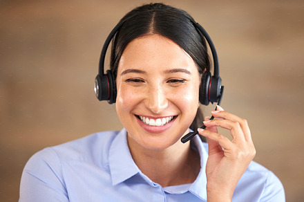 Closeup of smiling mixed race call centre agent talking to customers with a headset. Hispanic businesswoman answering calls, helping clients from an office. Headshot of customer service representative, a Photo by Peopleimages.com