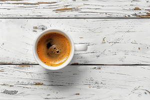 Flat lay of cup of coffee on wooden table, a Photo by AlyaAnd