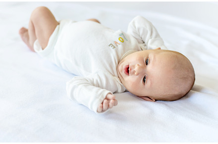 A newborn baby lies on a white bed, a Person Photo by yanadjana