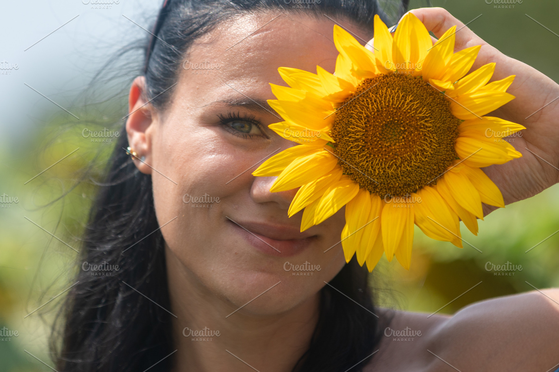 Smiling woman holding a bright yellow sunflower to her face outdoors, creating, a Person Photo by Ales Munt