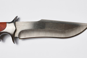 Close-up of a hunting knife blade and guard with a wooden handle, an Abstract Photo by ndanko