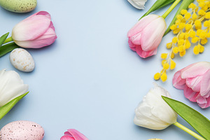 Easter eggs and tulips forming a frame on light blue background, a Holiday Photo by Olena Rudo