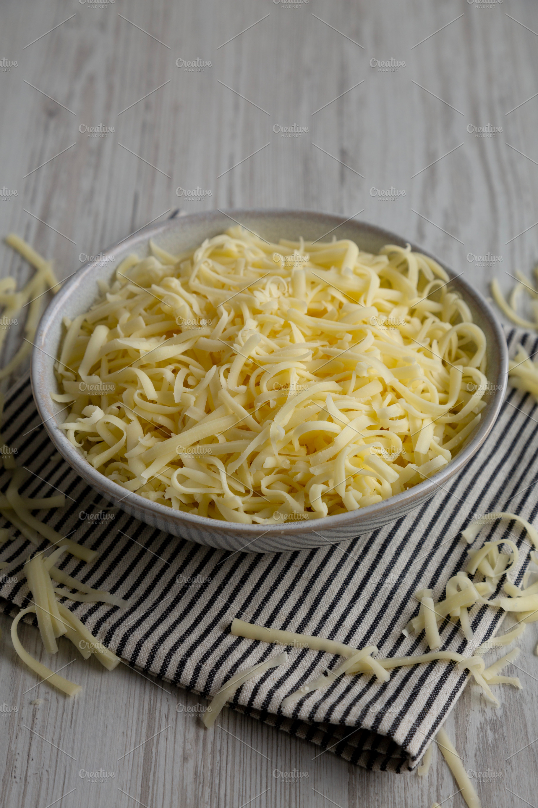 Organic Shredded Mozzarella Cheese in a Bowl, side view., a Food & Drink Photo by LiudmylaChuhunova