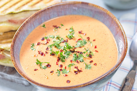 Bowl with Red bell pepper creamy soup, horizontal closeup
