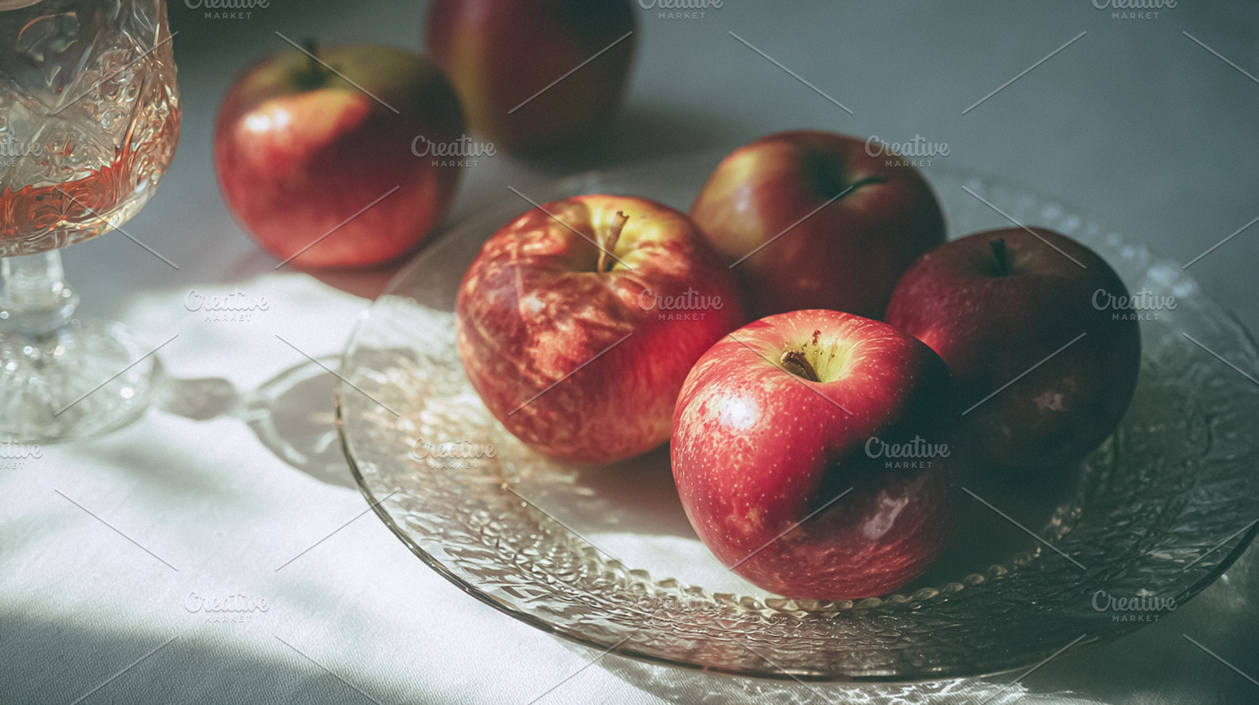 Fresh Gala apples sitting on a clear glass plate, receiving gent, a Photo by Studio ANNA