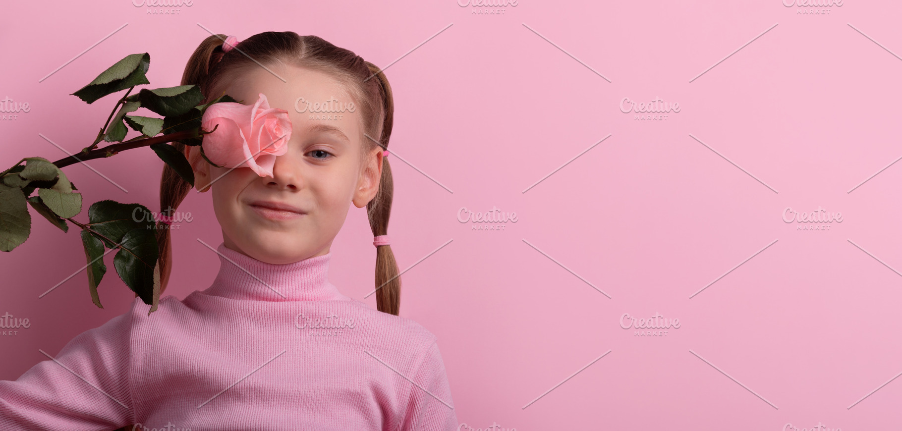 Cheerful young girl holding a pink rose in front of her eye, aga, a Person Photo by Ales Munt