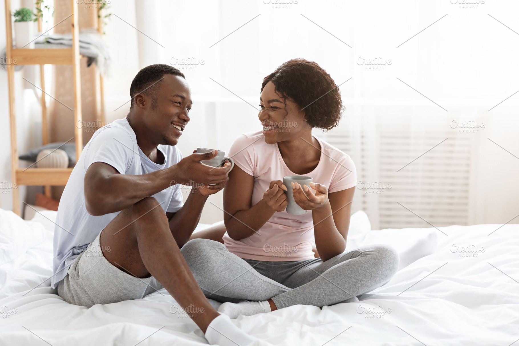 Happy black man and woman enjoying weekend at home together, a Photo by Prostock-Studio