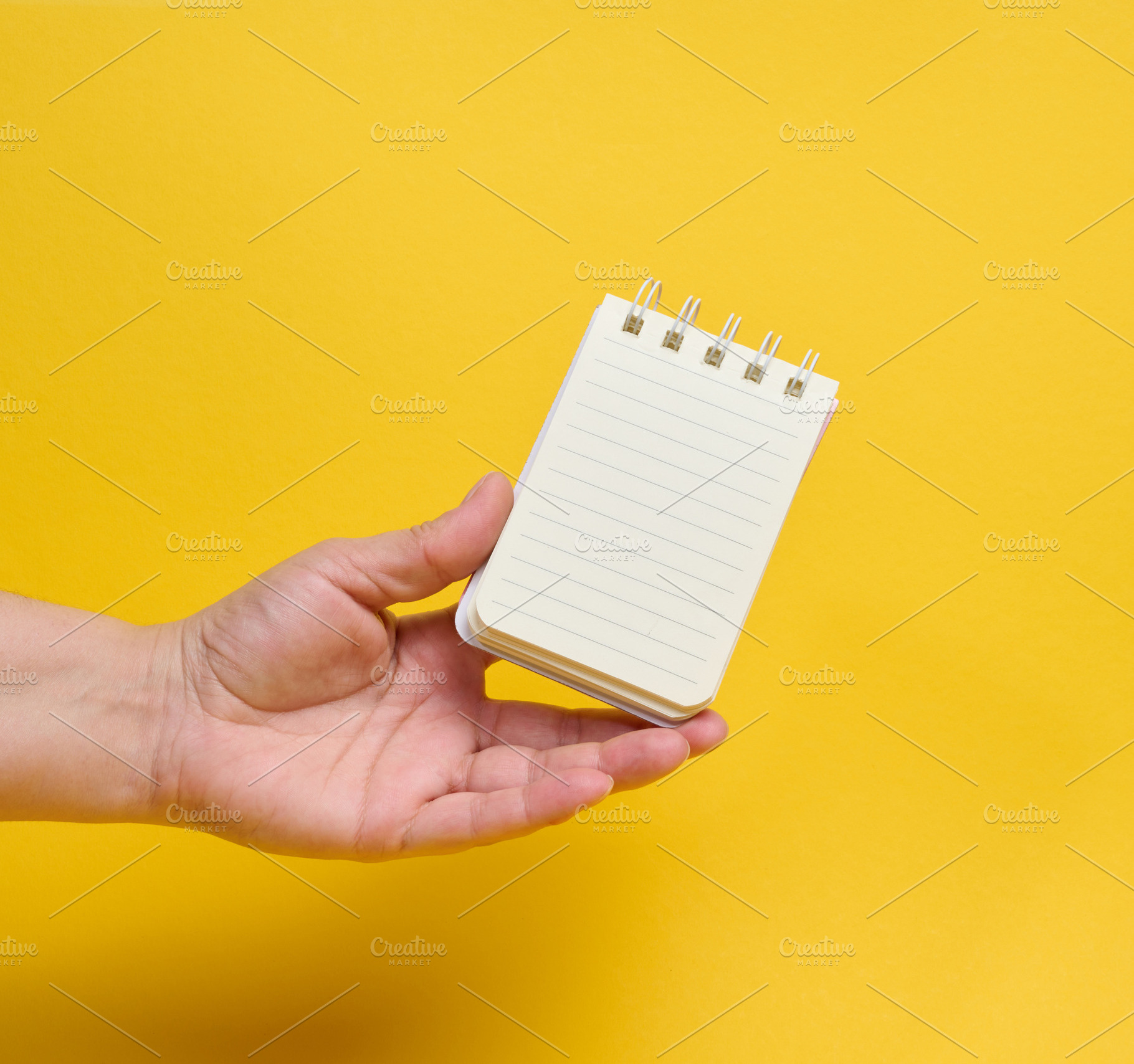 A person holding a small spiral-bound lined notepad on their pal, a Person Photo by ndanko
