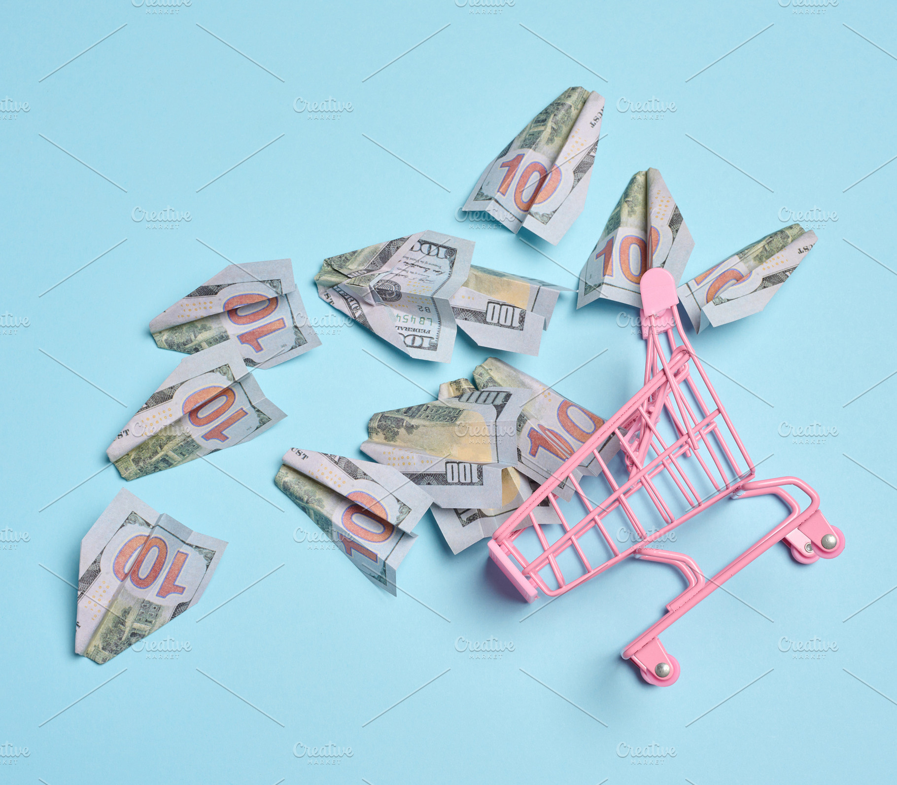 A pink metal shopping cart with scattered paper airplanes on a b, a Business Photo by ndanko