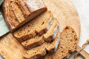 Slicing fresh whole grain rye bread on wooden board, a Food & Drink Photo by Olena Rudo