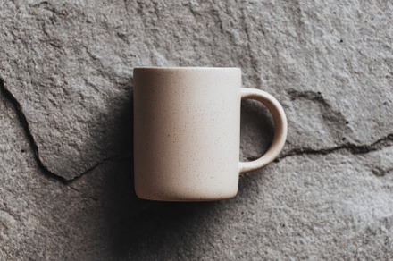 Beige ceramic mug on stone surface, a Food & Drink Photo by Virgo Studio