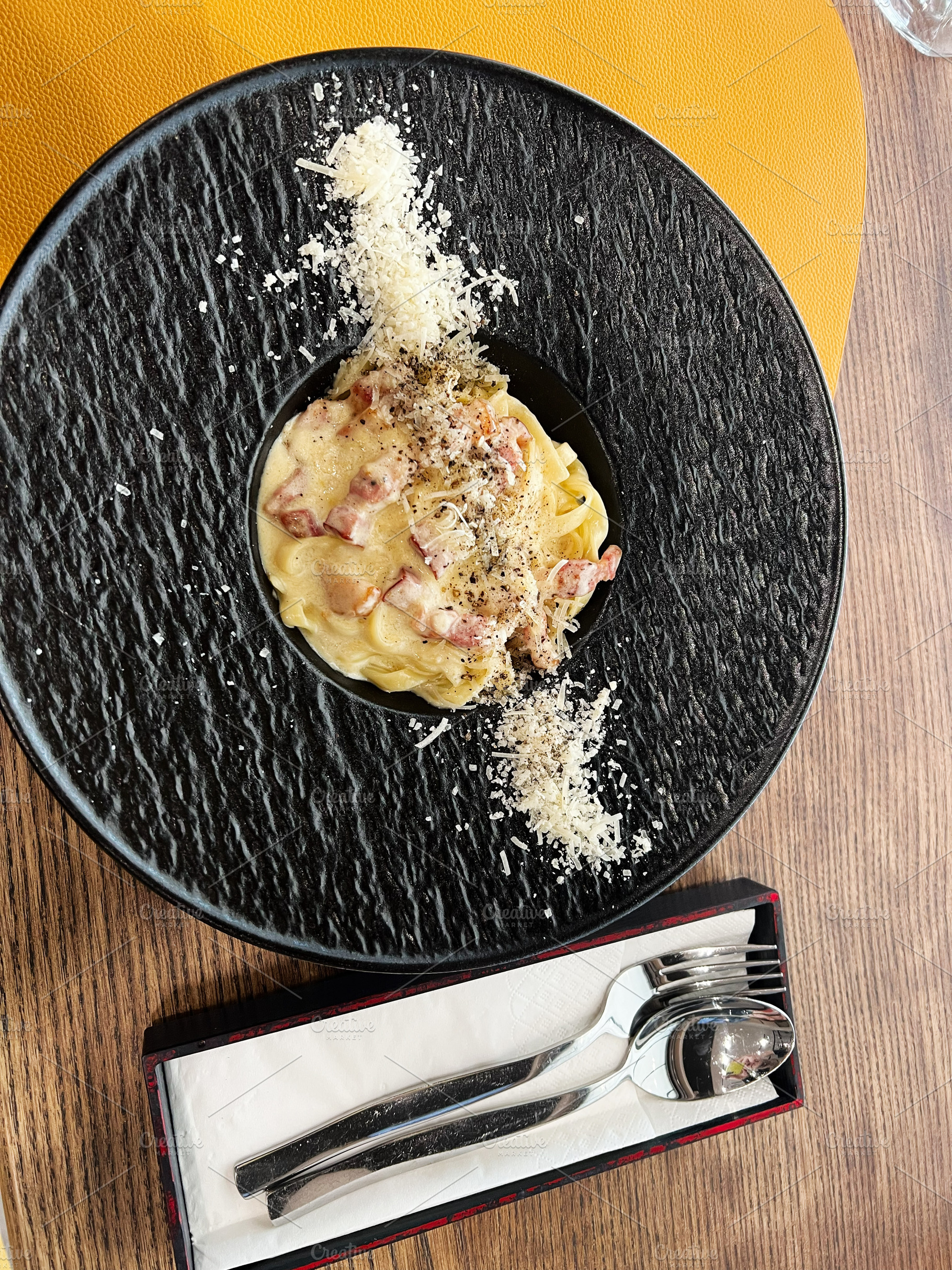 Delicious pasta carbonara served on a stylish plate with utensils on the side, a Photo by AS photostudio