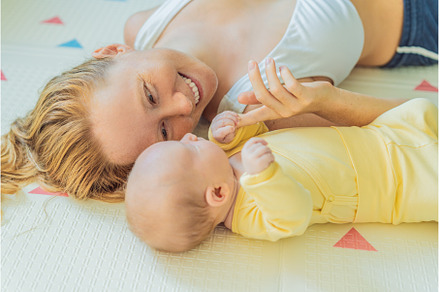 Mother and baby lying on a play mat