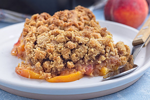 Delicious Peach Crisp or cobbler with brown sugar and oat streusel on plate, ho, a Food & Drink Photo by iuliia_n