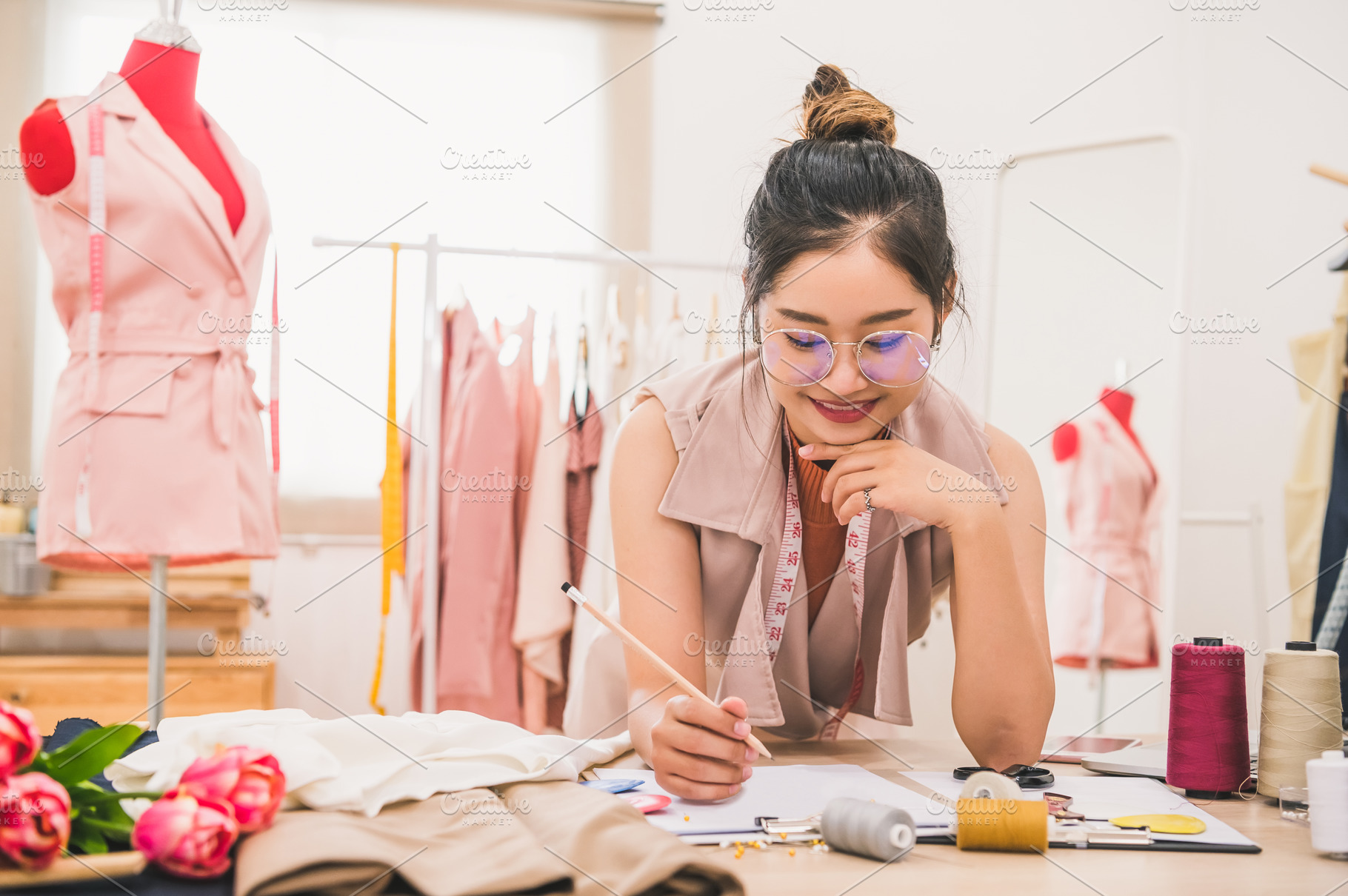 Attractive Asian female fashion designer working in home office, a Person Photo by Ministocker