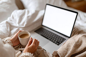 Freelancer enjoys a cozy work-from-bed setup with coffee in a comfortable home, a Technology Photo by AlyaAnd