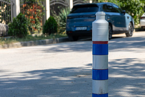 Plastic traffic bollard with blue reflective bands on a sunny city street, park, a Transportation Photo by Ales Munt