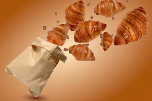 Fresh golden croissants and coffee beans fly out of a craft pape, a Food & Drink Photo by ndanko