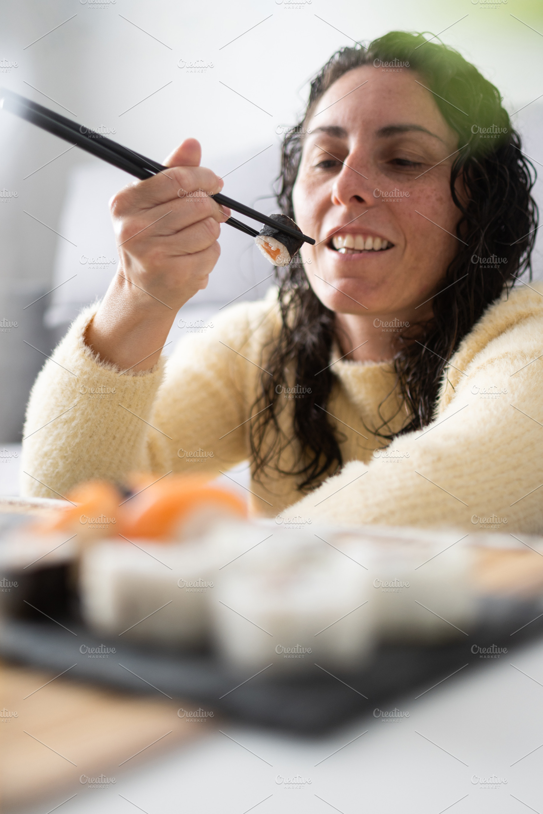 Woman eating sushi with chopsticks at home, a Person Photo by etorres69