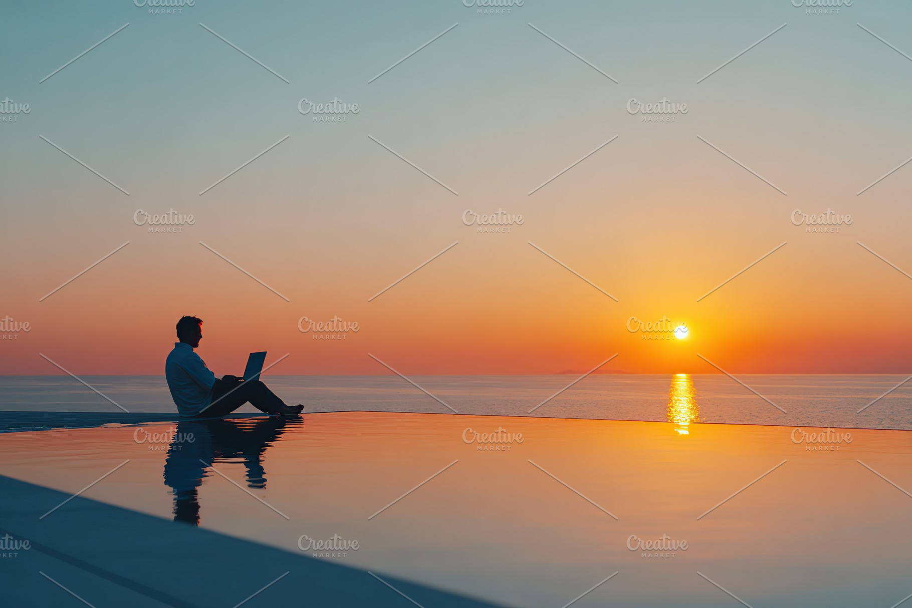 Man working on laptop by infinity pool at sunset over ocean, a Photo by AlyaAnd