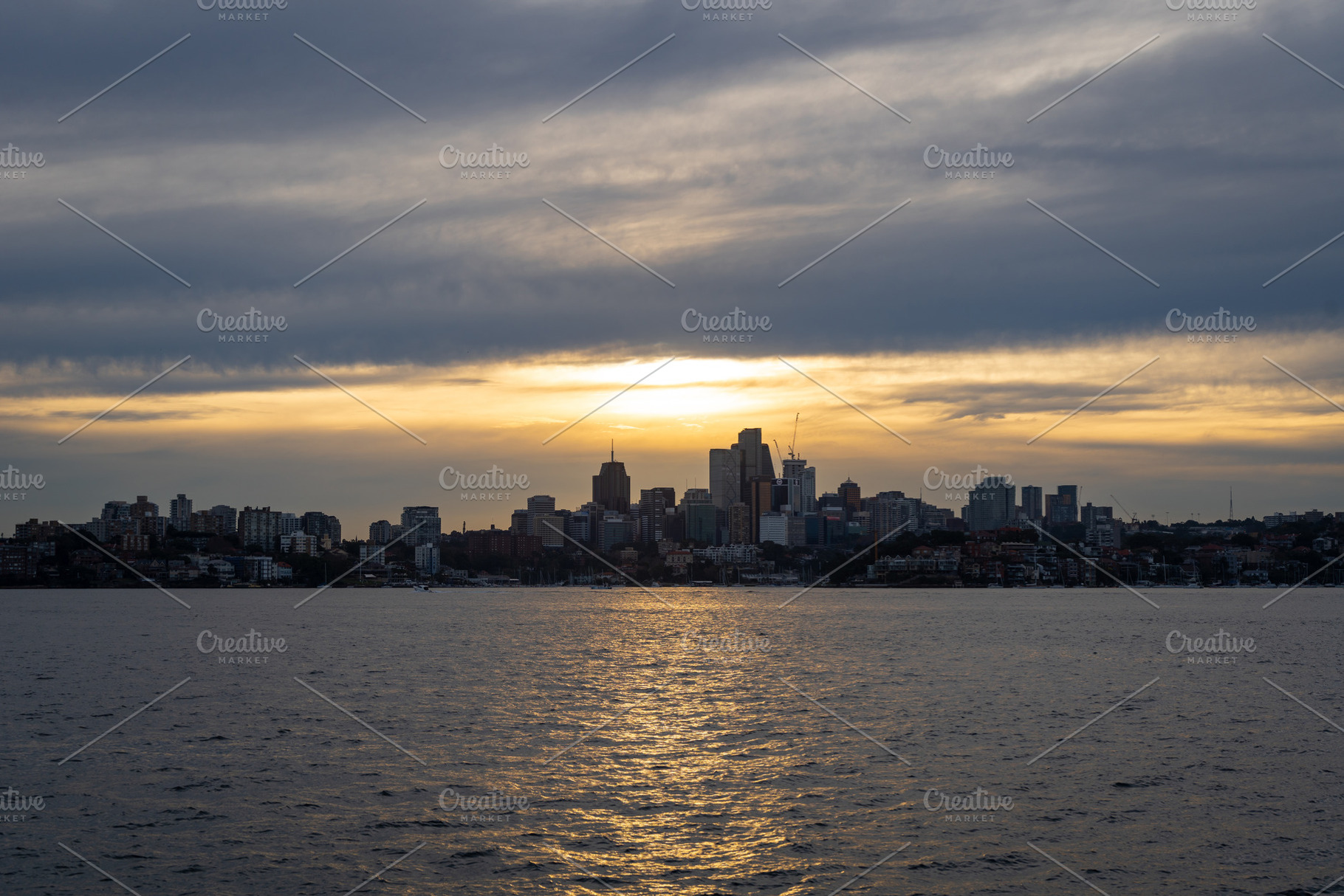 Sydney skyline at sunset with golden reflections on the water, a Nature Photo by GoodGoods