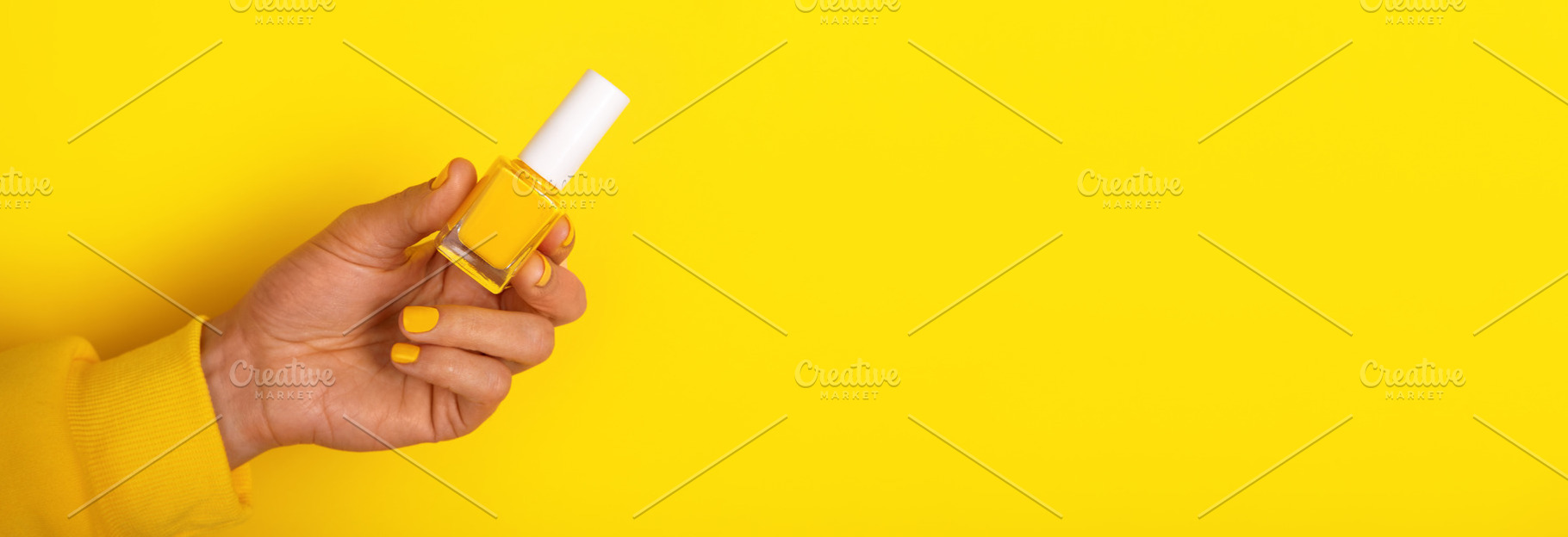 Close-up of a hand with yellow polished nails holding a yellow n, a Beauty & Fashion Photo by Ales Munt