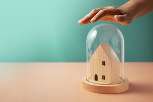 Hand covering small wooden house under glass dome, Home insuranc, a Photo by salmon.black