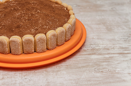 Round tiramisu cake on white wood table sprinkle with cacao powd, a Food & Drink Photo by TanaCh