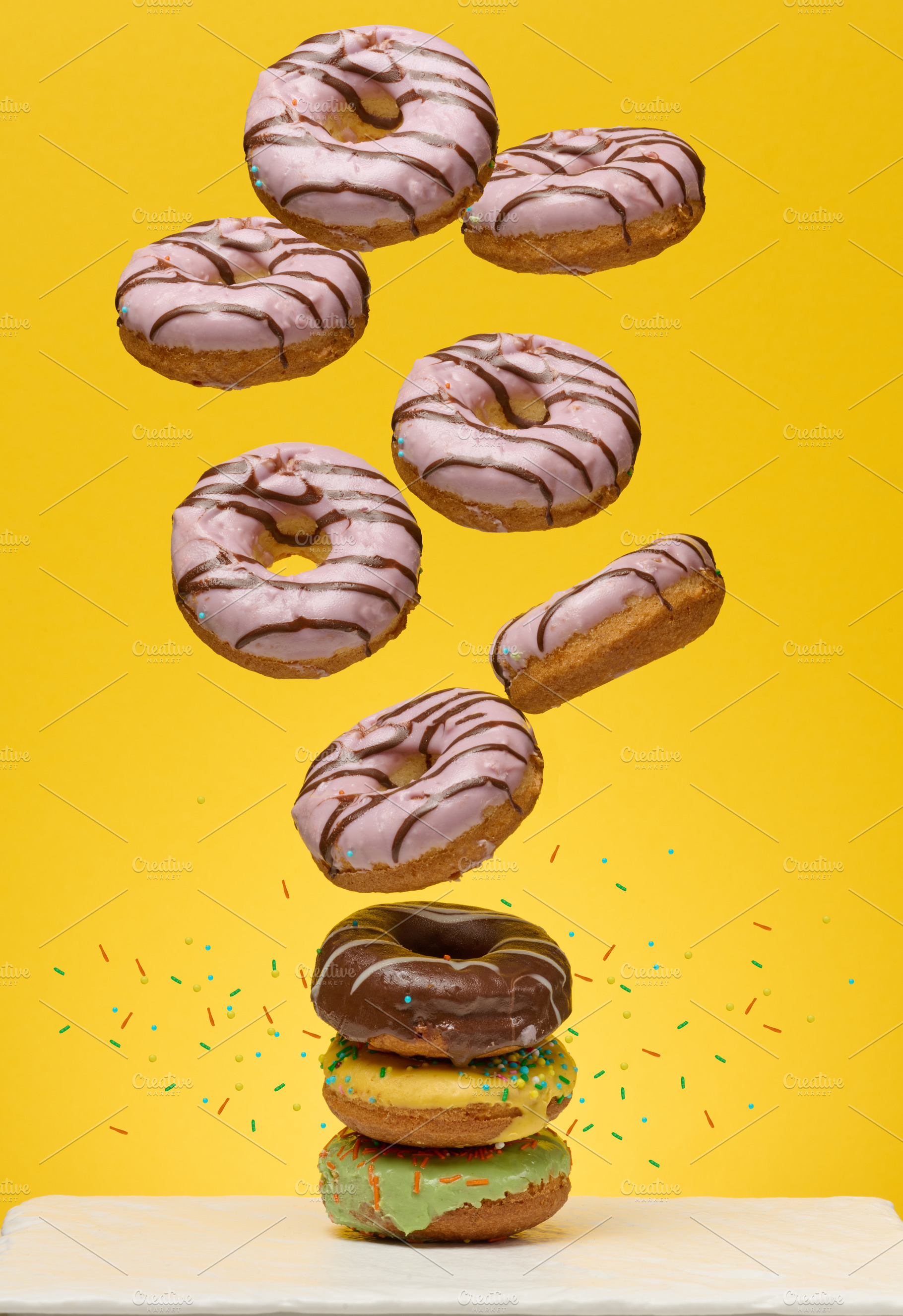 Stack of colorful glazed donuts with a variety of sprinkles and, a Food & Drink Photo by ndanko