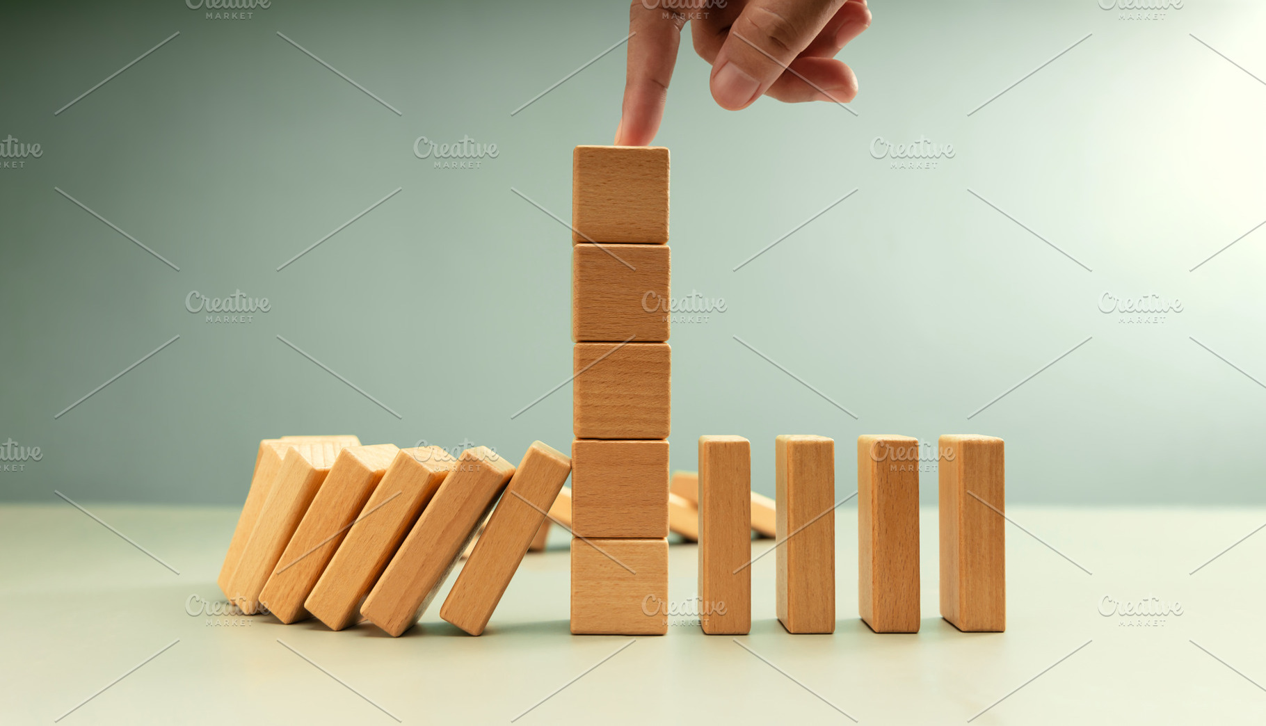 Falling row wooden blocks stopped by finger pushing one block up, a Photo by salmon.black
