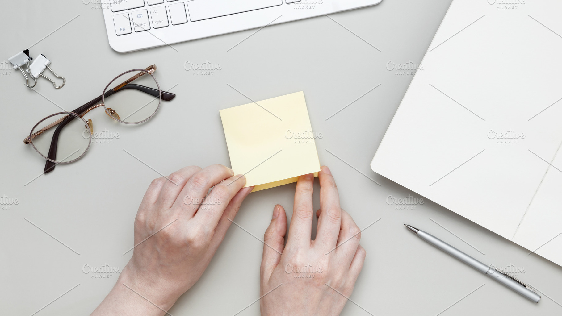 Female hand making reminder note on adhesive memo paper placed on tidy desk wit, a Photo by matucha