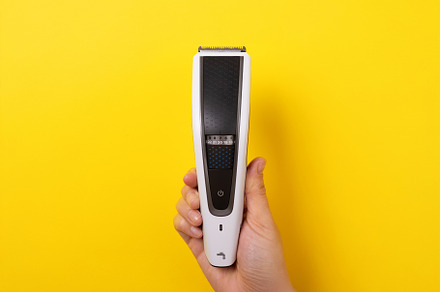 Close-up of hand holding a modern electric hair trimmer vertical