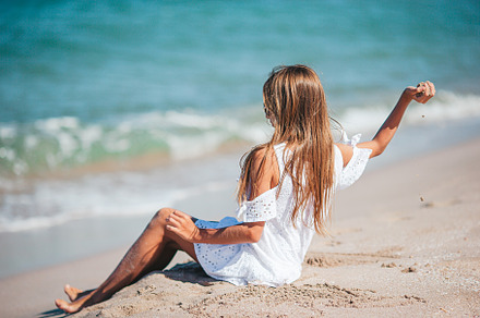Back view of adorable little girl with long hair in white dress on tropical bea, a Person Photo by travnikovstudio