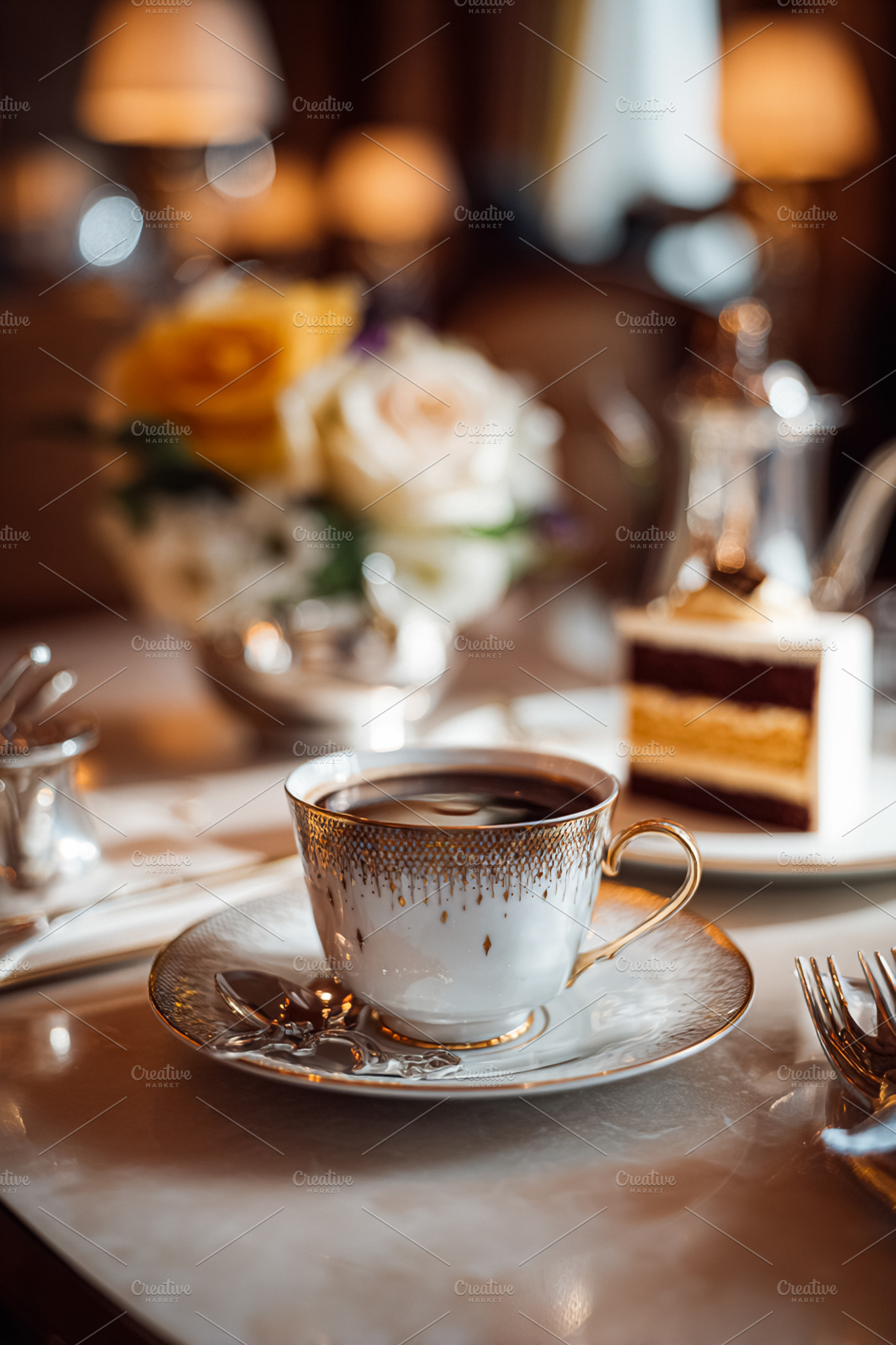 Coffee cup with gold decor and a delicious layered cake slice on, a Photo by Studio ANNA