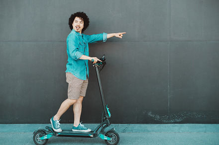 Man riding scooter, pointing forward, a Person Photo by SkyNext