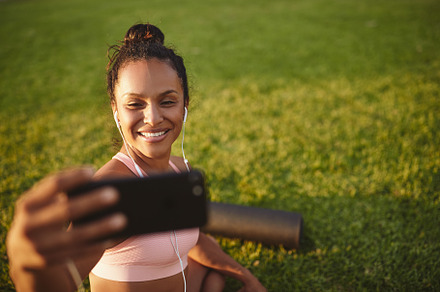 Smiling woman taking selfies in a park after doing yoga